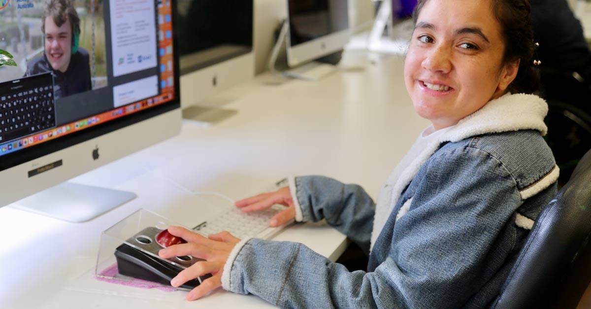 Bella, seated at a workstation, uses a Kensington trackball to work on digital design projects.