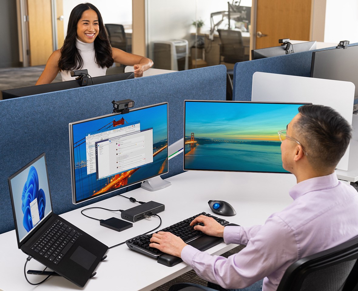 Woman talking to man who is typing on silent mechanical keyboard with wrist rest.