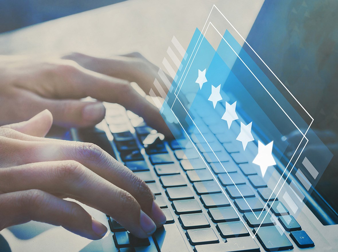 Close up to female hands typing on a laptop and rating with 5 starts.