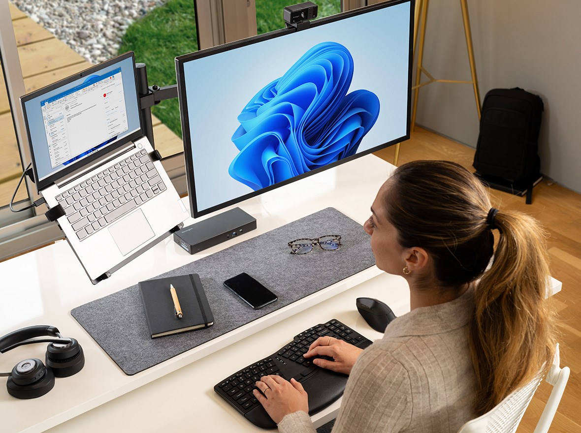 Woman working with her laptop and a dock plugged in to a 2nd screen.