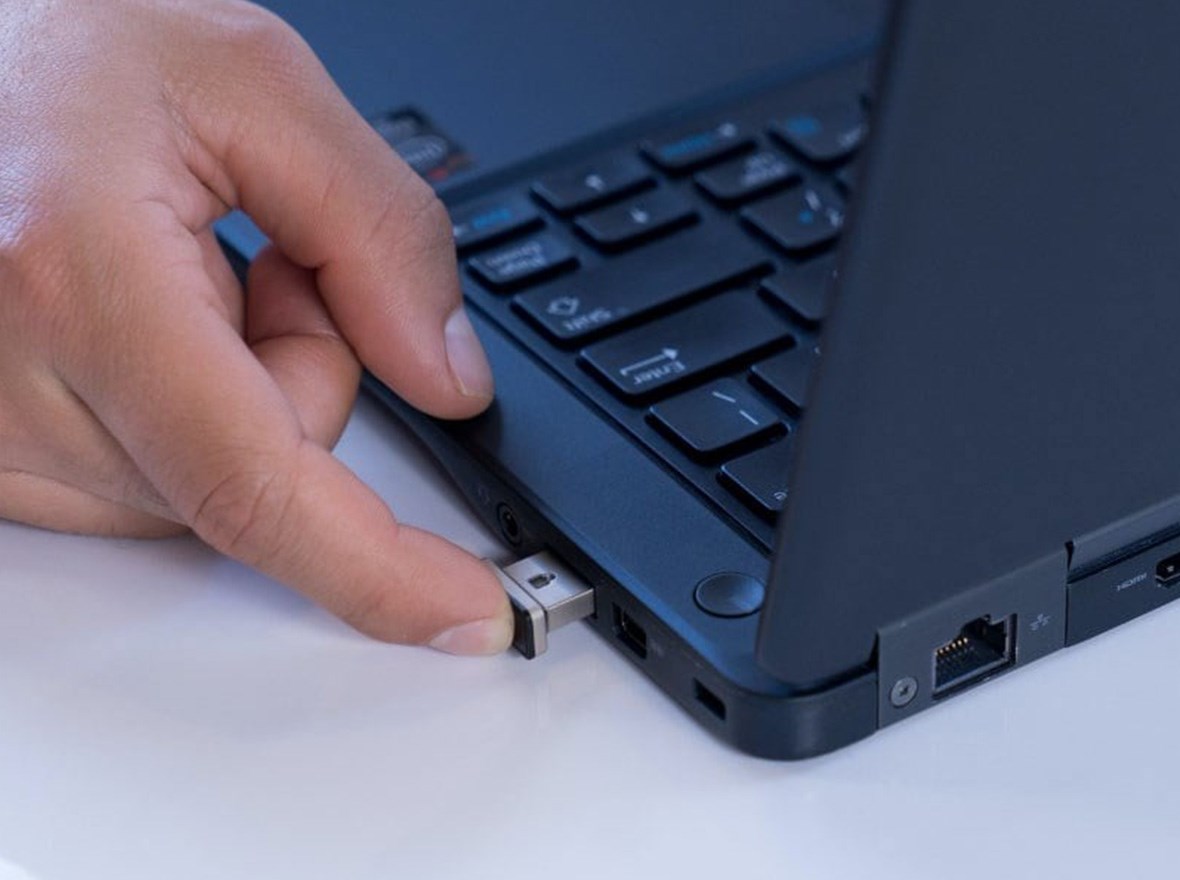VeriMark™ device connected to a laptop and a male fingerprint on it in order to unlock it.