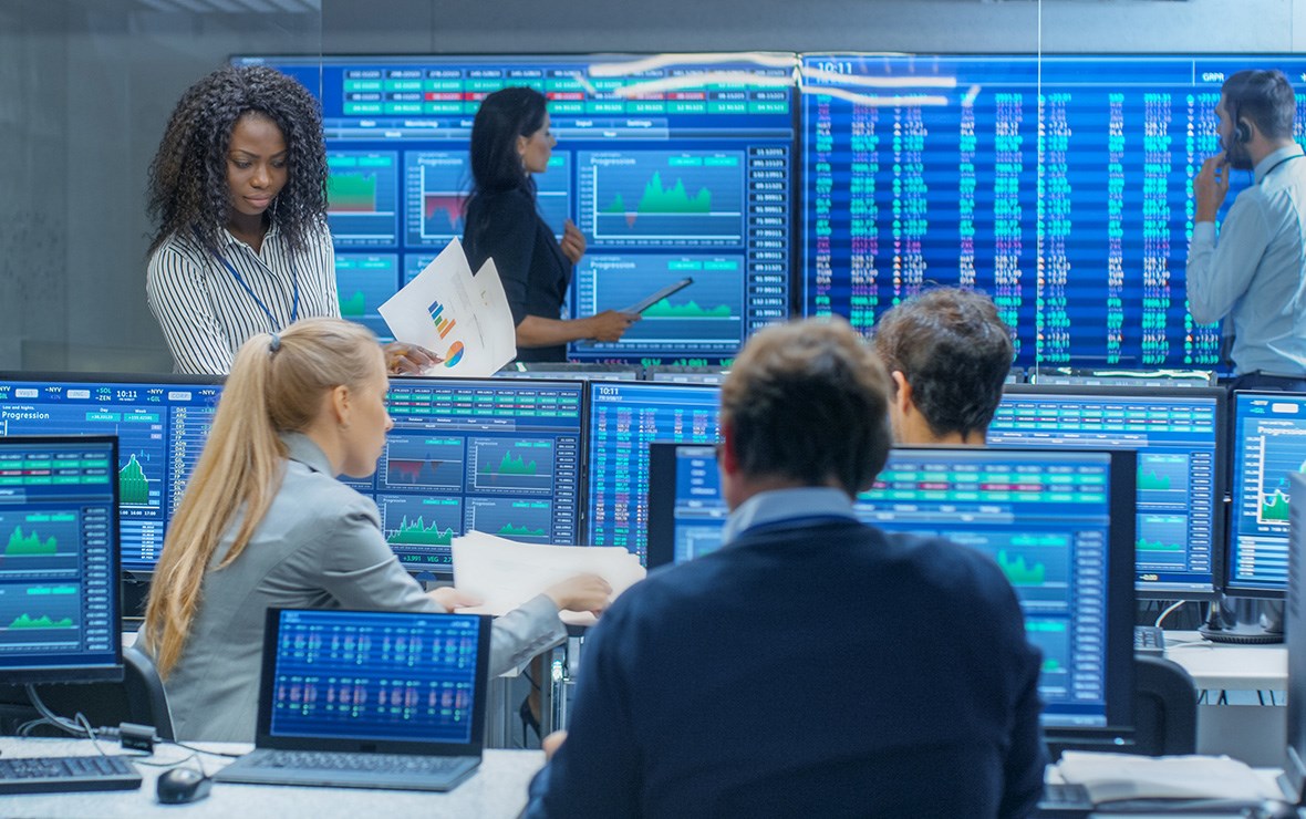Människor som arbetar på ett finanskontor med massor av skärmar.