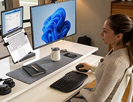 A person sitting at a desk using an ergonomic keyboard and mice